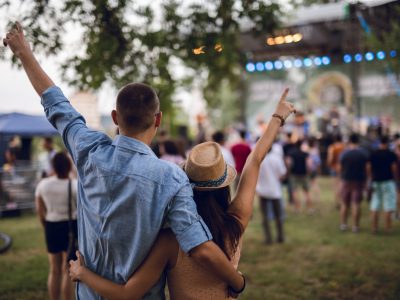 Young Caucasian couple toasting on a music festival.